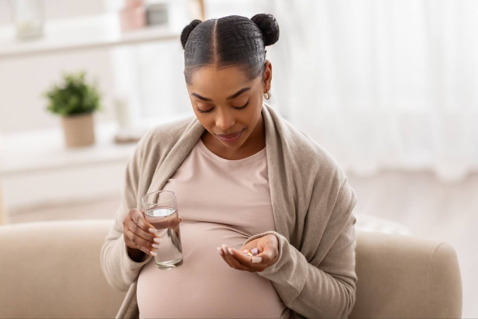 Pregnant black woman holding Medication and glass of water