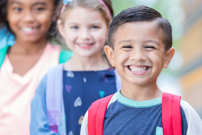 Smiling kids with backpacks going to school