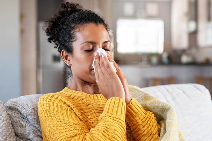 Woman blowing her nose into a tissue