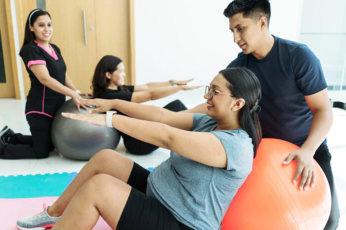 Pregnant women stretching with doula and partners