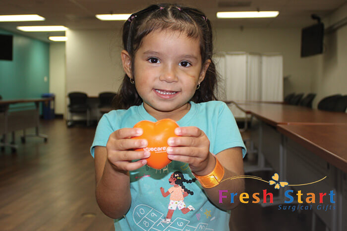 young child holding heart at clinic evaluation for reconstructive surgery from a medical condition.