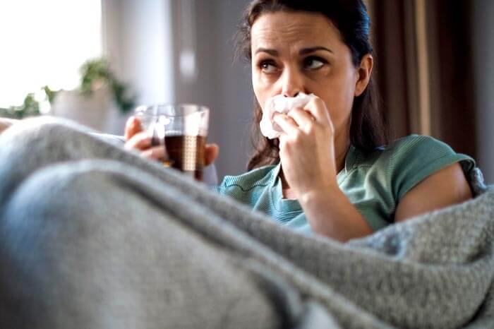 truecare-featured-image-flu-blog-700×466 Sick woman lying in bed and blowing nose