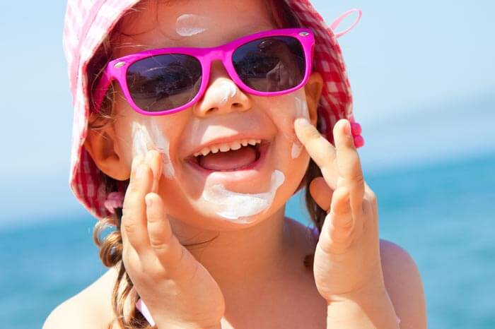 Chica unge su crema protectora de la cara en la playa