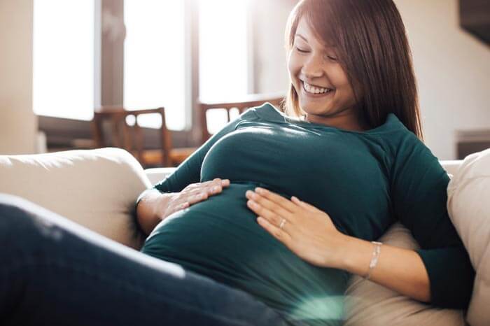 Mother touch her baby bump to feel the baby.